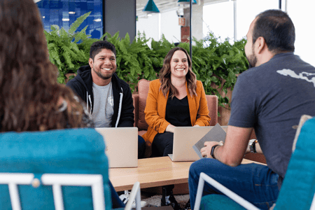 Man and a woman sitting at a table using laptops